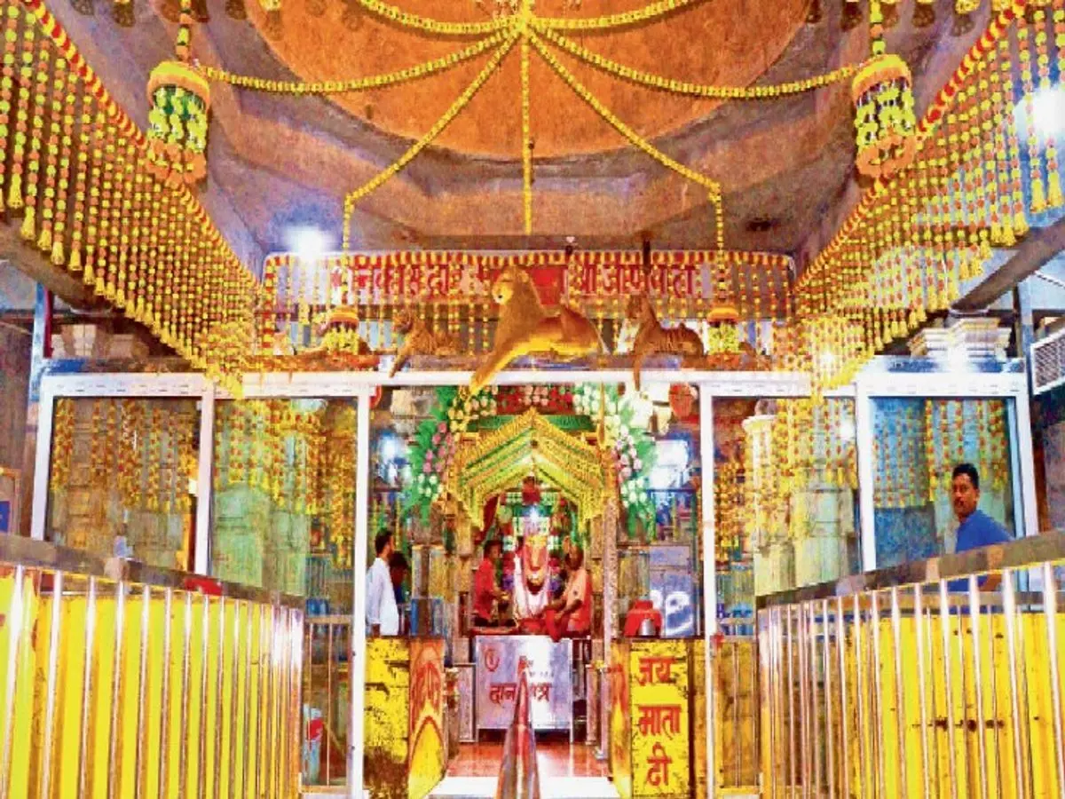 Main mandap of Jeen Mata Temple decorated with hanging marigold garlands, golden lion statues above the sanctum entrance and 'Jai Mata Di' railings leading to the Goddess